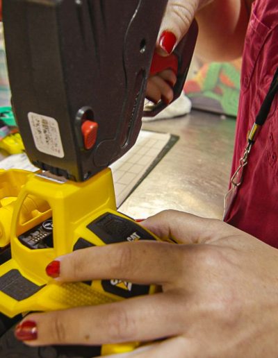 Volunteer adding a label to a toy excavator at Hangers of Hope Thrift Stores Benefiting the Bethesda Health Clinic in Tyler, TX