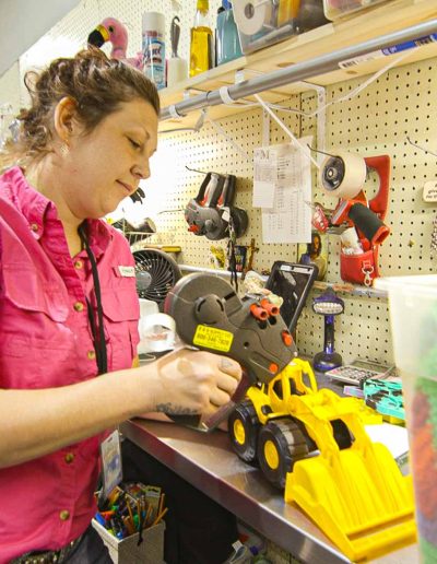 Volunteer adding a label to a toy excavator at Hangers of Hope Thrift Stores Benefiting the Bethesda Health Clinic in Tyler, TX